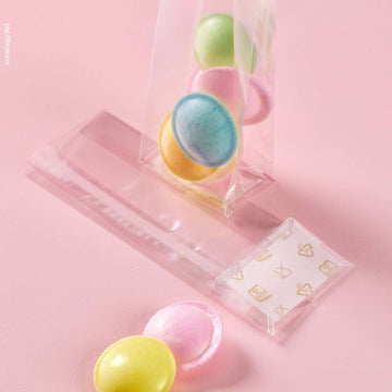 Sacchetto trasparenti a fondo quadro, ripieni di dolci, su sfondo rosa. Mostrato pieno e steso